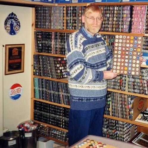 A collector standing next to the world's largest collection of bottle caps.